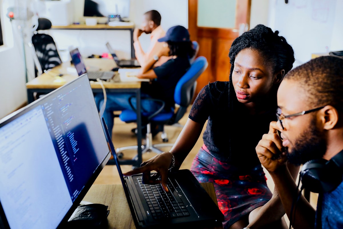 Two engineers reviewing code on a monitor